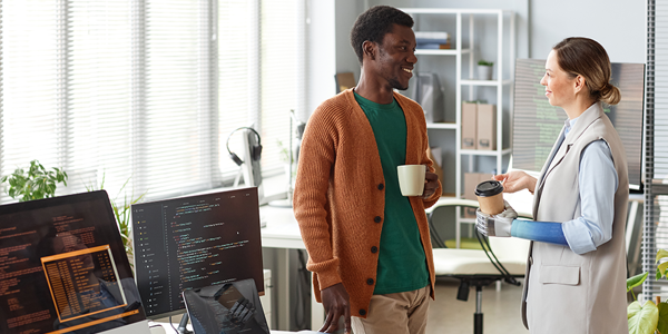 Smiling woman with bionic arm talking to colleague during coffee break