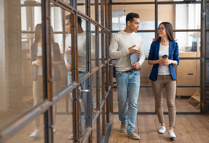 Business man and woman walking in office hallway talking