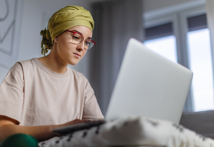 Young adult woman working on laptop in their apartment